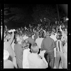 President Johnson standing on car and surrounded by supporters