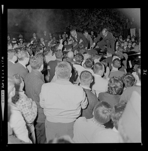 President Johnson standing on car and surrounded by supporters