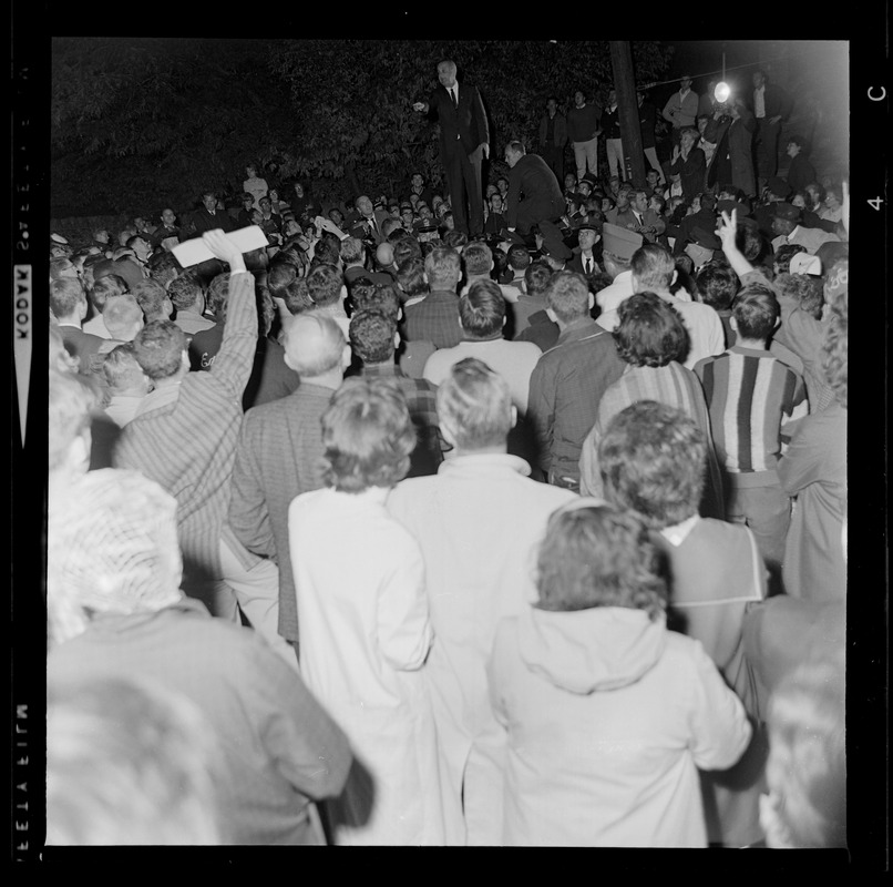 President Johnson standing atop a car truck and addressing crowd