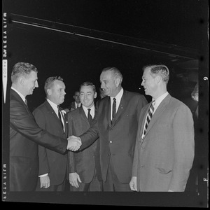 President Johnson shakes a man's hand while standing with Robert Crane, second from left, and Governor Peabody, far right
