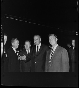 President Johnson waves to the camera while standing with Massachusetts State Treasurer Robert Crane, far left, and Governor Peabody, far right