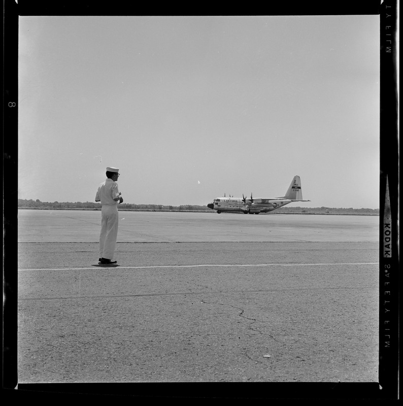 Military man on an air landing strip with a plane in the distance