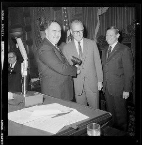 John F. X. Davoren shakes hands with another man as Governor Volpe looks on