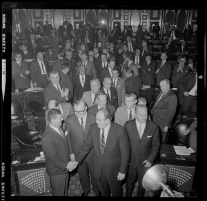 Former House Speaker John F. X. Davoren is surrounded by legislators as he walks down the aisle out of the House chamber after being named Secretary of State