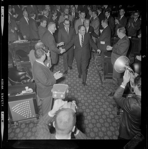 Former House Speaker John F. X. Davoren is surrounded by legislators as he walks down the aisle out of the House chamber after being named Secretary of State