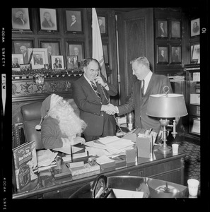 John F. X. Davoren on the phone and shaking a man's hand as a seated as Santa Claus