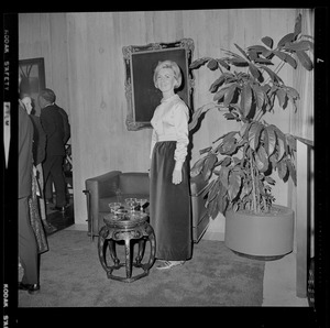 Woman posing near large plant with a painting in the background during the opening of Boston City Hall