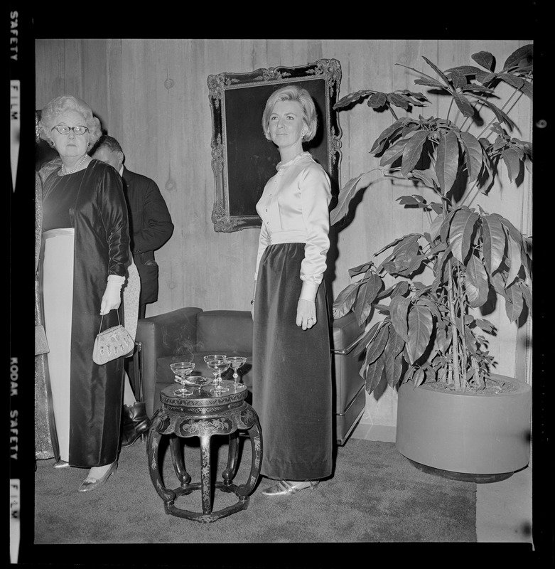 Woman posing near large plant with a painting in the background during the opening of Boston City Hall