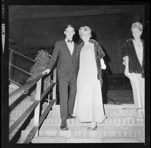 Woman in floor-length dress and fur with a man walking down brick stairs at the opening of Boston City Hall