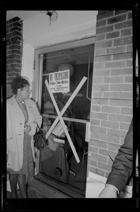 A woman walking by a door of the Boston Redevelopment Authority South End office with a "No Trespassing" sign in it