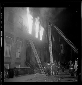 Three firefighter ladders against the burning building
