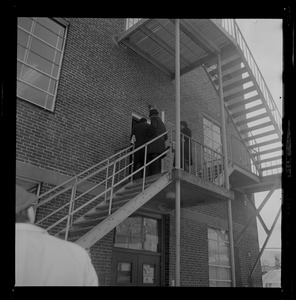 Group of people standing on fire escape of second level of a building