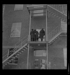 Group of people standing on fire escape of second level of a building