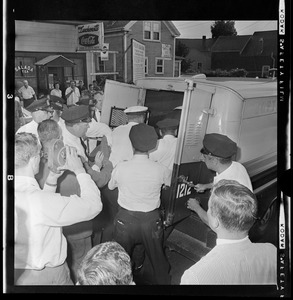 Police officers putting a person in the back of a police department wagon