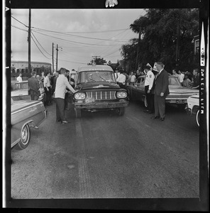 People gathering in the street around a police car