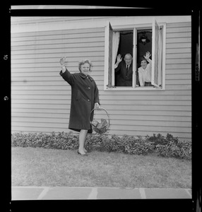 Marjorie Hall Brown waving to the camera while Walter Brown and daughter Marjorie are waving from inside the window