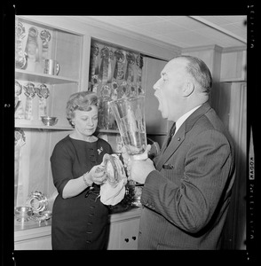Walter Brown breathing on glass object, while his wife Marjorie polishes the top