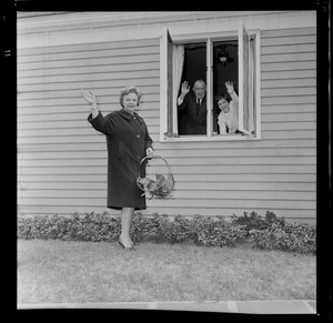 Marjorie Hall Brown waving to the camera while Walter Brown and daughter Marjorie are waving from inside the window
