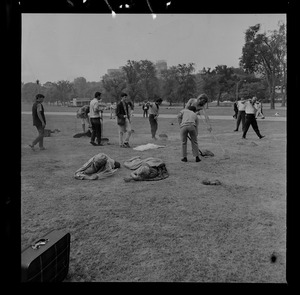 People raking and working in the Boston Common while two people lay down in the grass