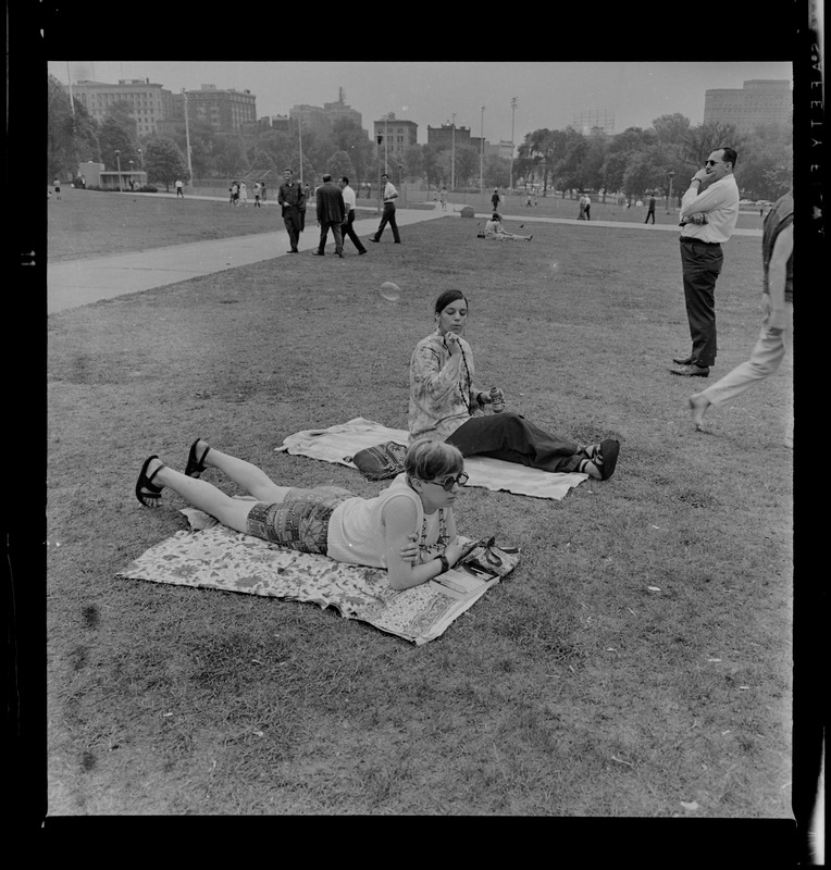 Two women sitting on rugs in Boston Common
