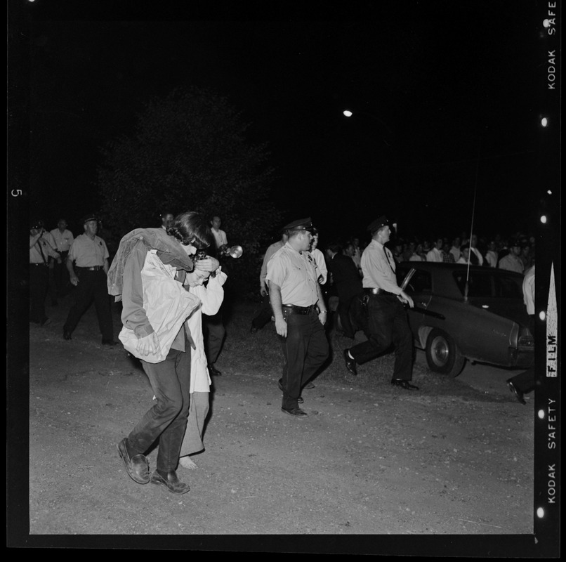 Policemen walking in Boston Common as two people help each other walk