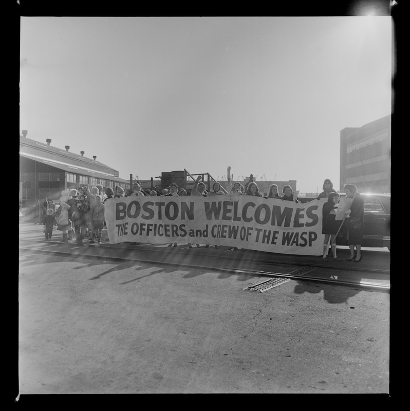 People holding a welcome banner for officers and crew of the USS Wasp