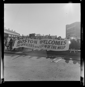 People holding a welcome banner for officers and crew of the USS Wasp