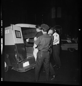 Police officers putting a man into the police wagon