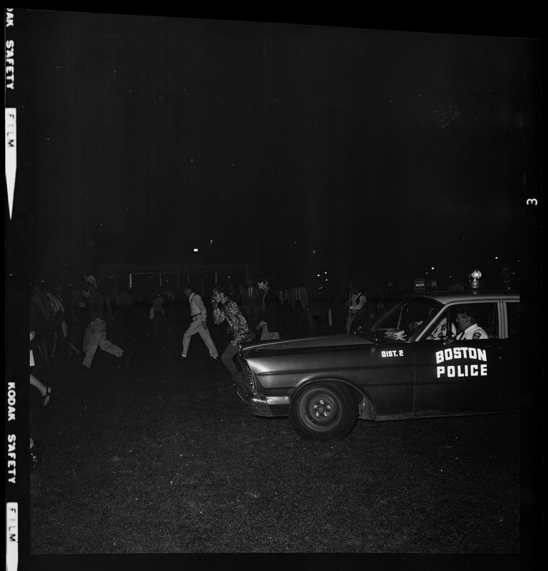 Police officer in a cruiser pulls up near a gathering crowd