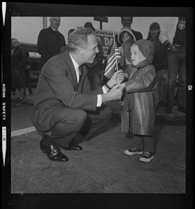 Kevin White crouches down to chat with a young child during the Bunker Hill parade