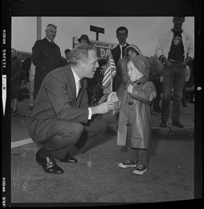 Kevin White crouches down to chat with a young child during the Bunker Hill parade