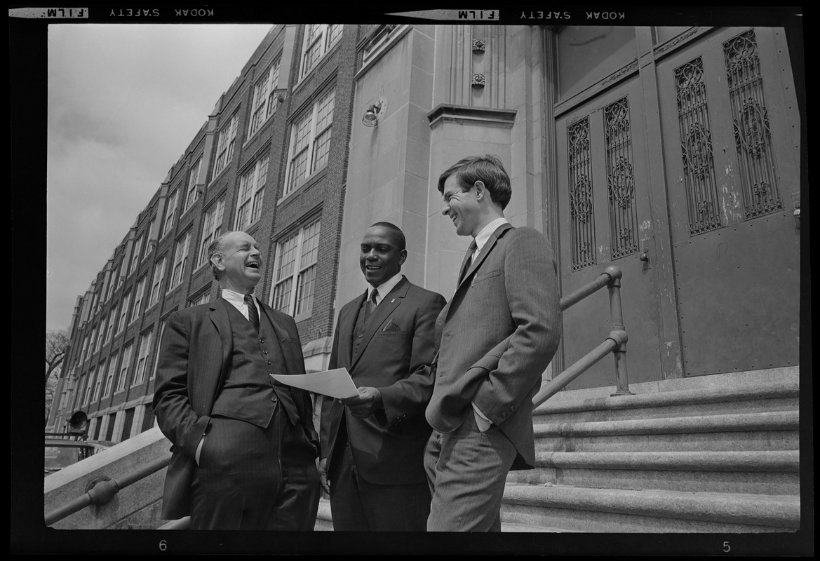 Three men in conversation and laughing on steps of a building