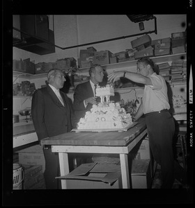 Mayor Kevin White and two other men in conversation while standing around a cake