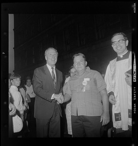 Mayor Kevin White shaking a man's hand with Rev. Dominic Radighieri looking on