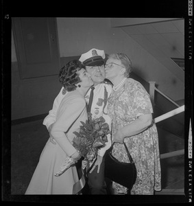 Patrolman wearing a Department Medal receives kisses from two women