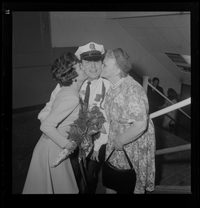 Patrolman wearing a Department Medal receives kisses from two women
