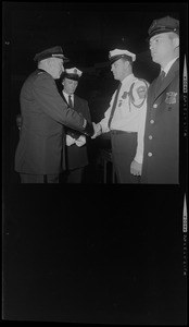 Police official shaking another police officer's hand during awards ceremony