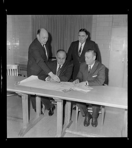 Captain Edw. F. Fahey of the MDC points to map of roadway of new pike--soon to open to the Northeast Expressway to Capt. Peter Bille of MDC (Old Colony Div), Capt Mike Faherty of the State police (seated right), and standing in the background is Boston Police Deputy Superintendent James Buchanan