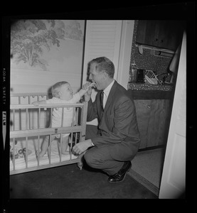 Kevin White kneels to son Christopher in his play pen