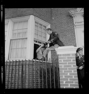An officer climbing into a window with the help of another officer
