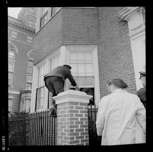 An officer climbing into a window with the help of another officer