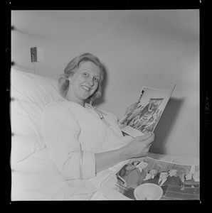 Margarita Bellotti seated and holding two photographs up to a nurse