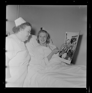 Margarita Bellotti seated and holding two photographs up to a nurse