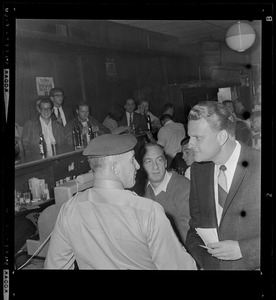 Evangelist Dr. Billy Graham inside a bar with a large gathering of people