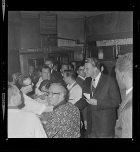 Evangelist Dr. Billy Graham inside a bar with a large gathering of people