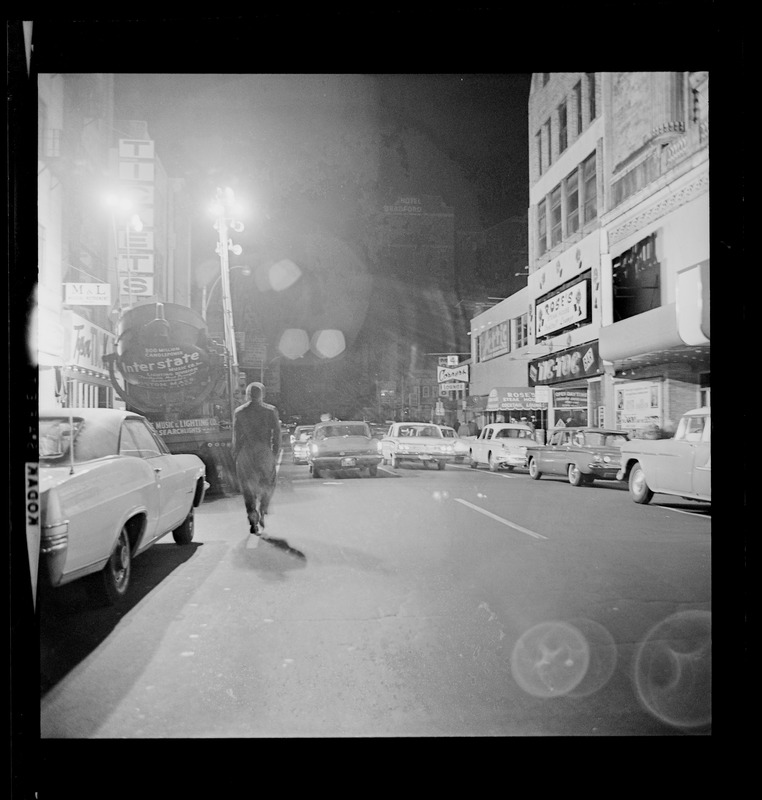 Man walking down the street with cars parked on either side