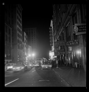 View of a street during blackout with pedestrians and cars parked on either side