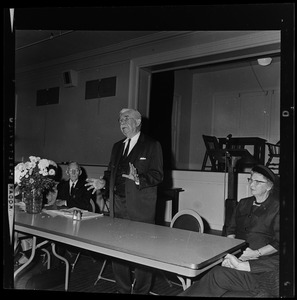 Man at a table addressing a room