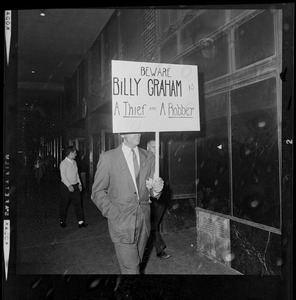 Protester with a sign that reads "Beware Billy Graham a thief and a robber"