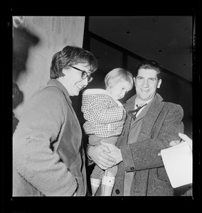 Woman and man holding a child and talking with a reporter